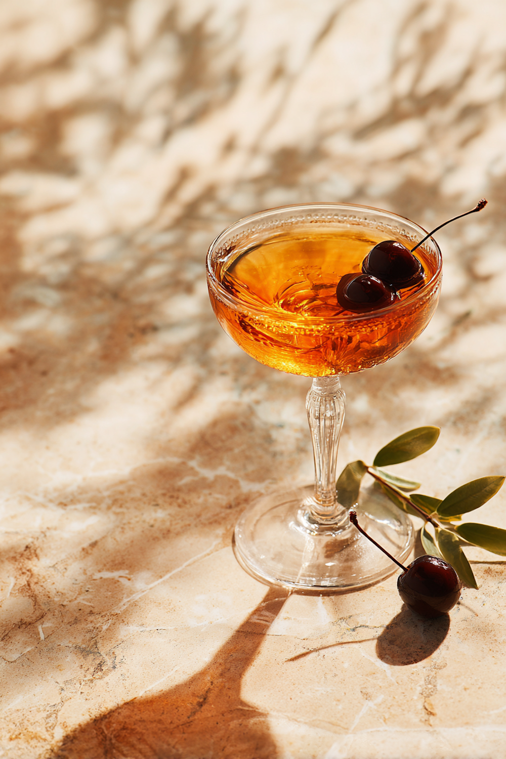 Amber cocktail with cherries in a coupe glass